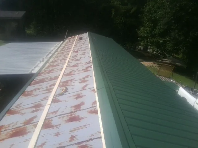 Old rusted panels beside newly installed green metal roofing — Wind Damage Roof Repair by Roofing Brothers in Fayette