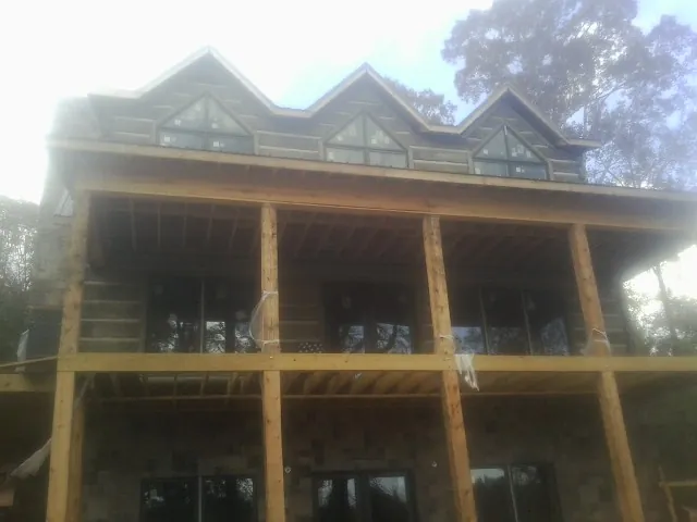 Dormers and porch framing on a large log home under construction — Roof Coating work by our crew in Fayette