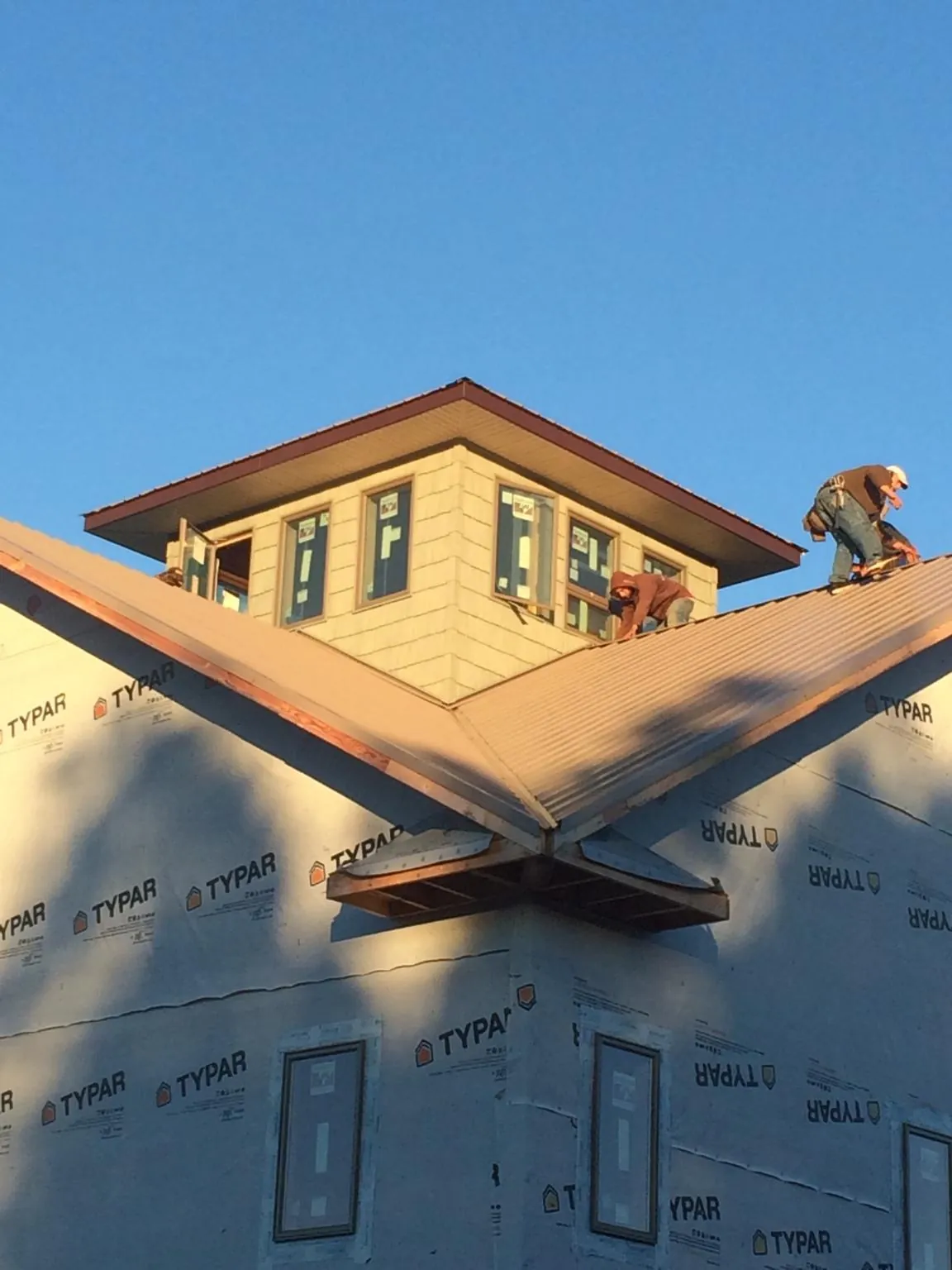 Roofers working around a rooftop cupola on a new metal roof at sunset — Roof Waterproofing in Fayette by Roofing Brothers